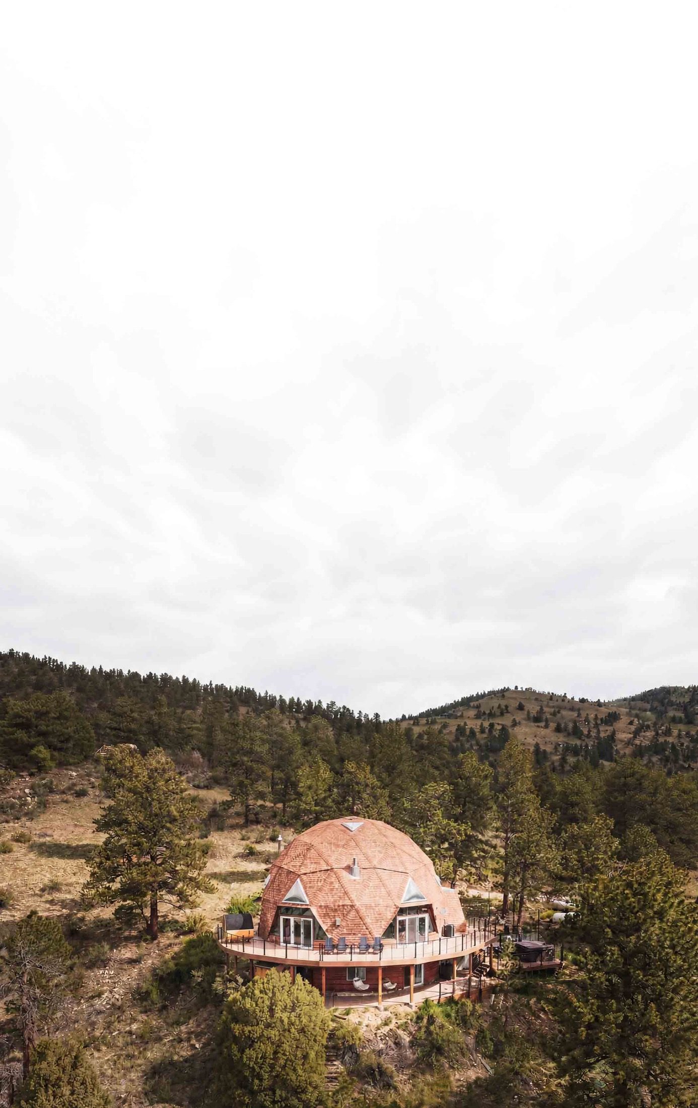 The Luna Dome geodesic dome on a forested hillside under a wide blue Colorado sky near Idaho Springs
